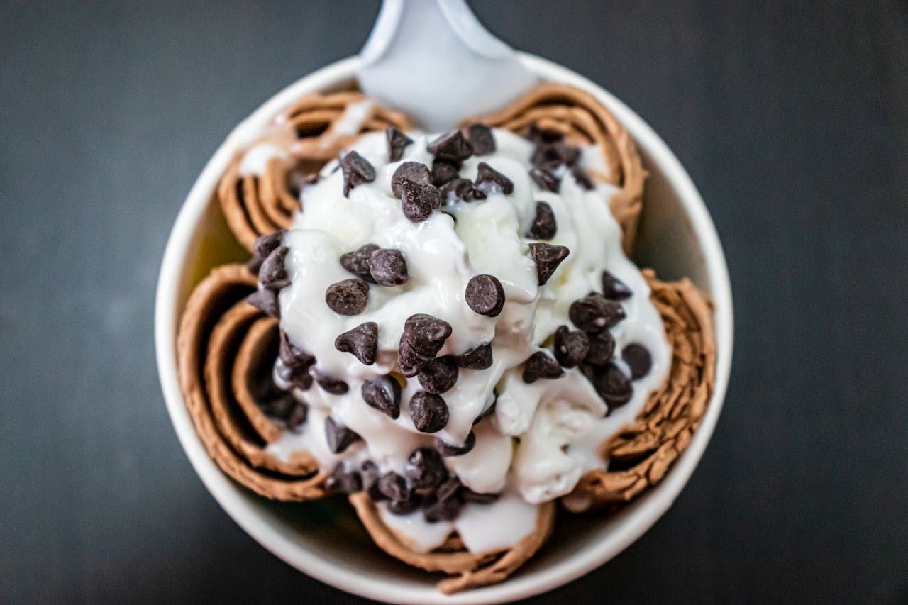 Close-up of rolled ice cream topped with creamy vanilla and chocolate chips, perfect dessert treat.