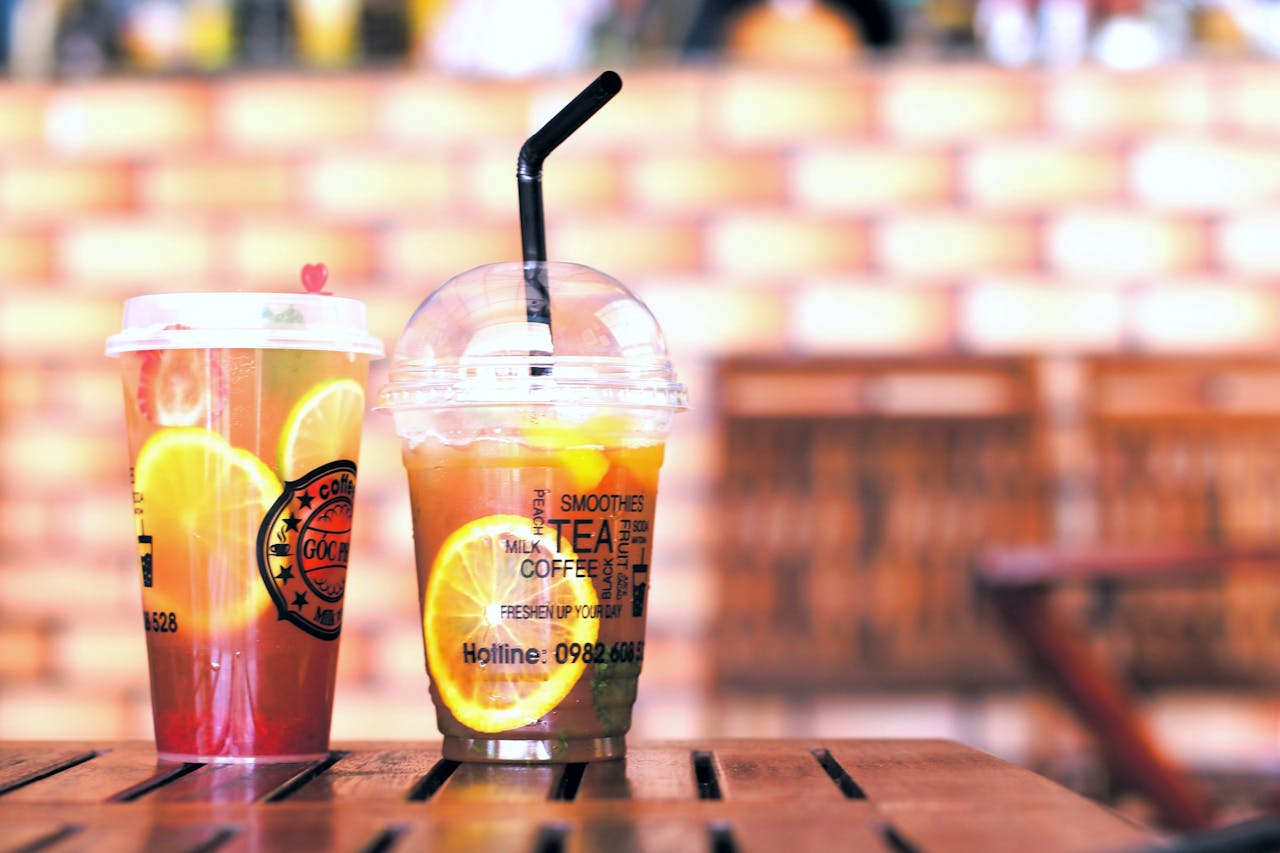 Colorful citrus iced teas on a wooden table, perfect for summer refreshment in a cafe setting.