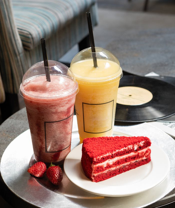 Indulge in fruit smoothies paired with a rich red velvet cake slice for a delightful treat.
